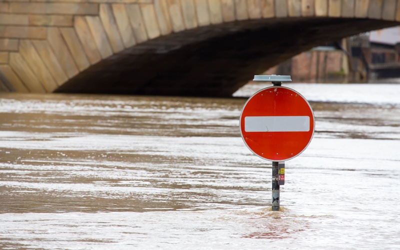 a flooded street with a partly submerged no entry road sign - Credit: Shutterstock - northallertonman - 1650607627